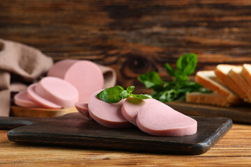 Boards with slices of tasty boiled sausage, bread and basil on brown wooden background © Pixel-Shot