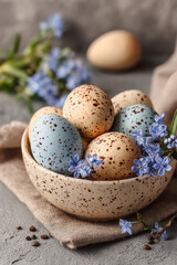 Obraz premium Naturally decorated Easter eggs in a speckled bowl with delicate blue spring flowers
