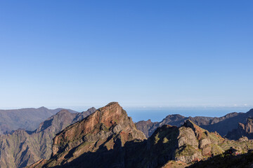 Fototapeta premium PR 1 hiking trail ridges on Madeira Portugal, jagged volcanic peaks above Curral das Freiras with deep green valleys and distant Atlantic haze