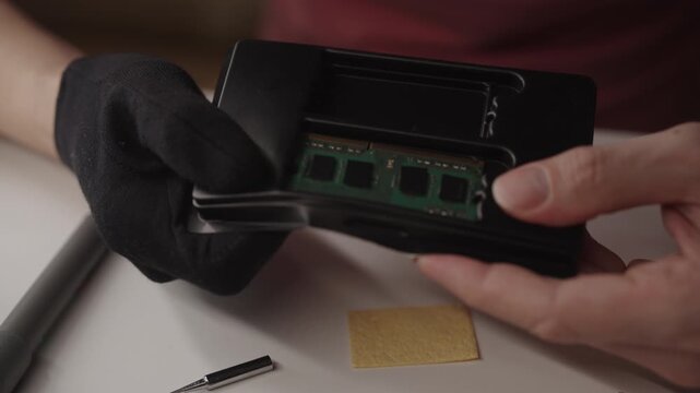 Close-up of man unboxing new computer memory module from anti-static packaging, holding ram component for hardware upgrade, focusing on system maintenance. Shooting in slow motion.