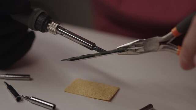 Close-up of person using soldering iron to repair ram module, performing electronic component installation and diagnosing hardware issues on computer memory stick, closeup. Shooting in slow motion.