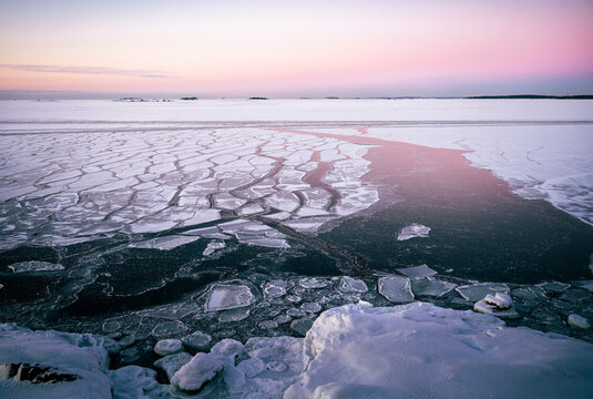 Frozen Baltic Sea with cracked ice under pastel winter sky in Finland