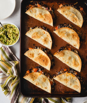 Top view of sheet pan baked beef and bean tacos with guacamole.