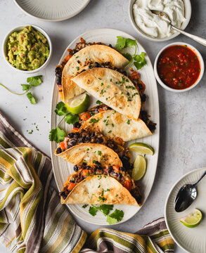 Top view of platter of beef and bean tacos with guacamole, salsa.