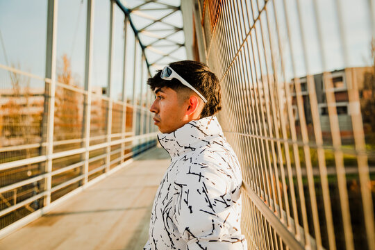 Thoughtful man in patterned jacket on a modern metal bridge outdoors