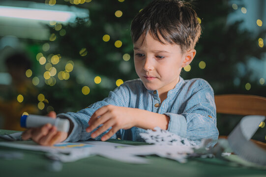 Child making paper snowflake decorations for Christmas indoors