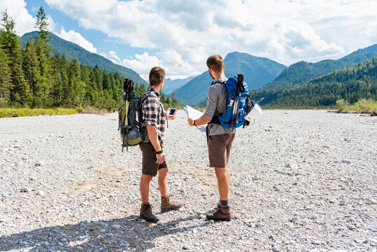 Brothers hiking with backpacks and navigating outdoors in summer