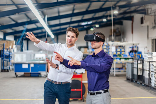 Businessmen using VR glasses during meeting in production hall