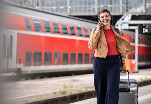 Business traveler making call with luggage at train station