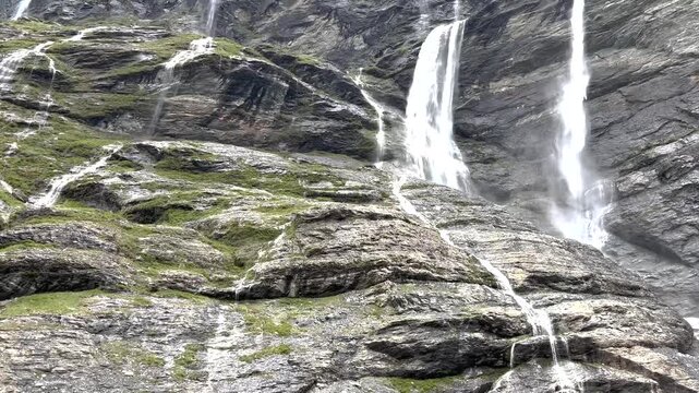 Look up to the waterfalls descending from mountain wall. New Zealand nature scene. Earnslaw Burn