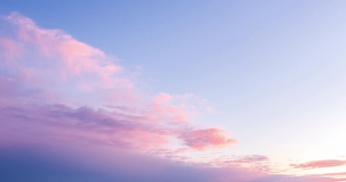Timelapse of soft pastel clouds moving across a sunset sky. Pink and blue tones create a calm atmospheric background, ideal for nature, relaxation, and time passing concepts.