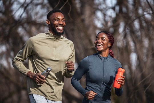 Happy black couple running together outdoors for fitness