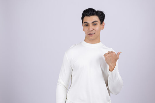 Man in white shirt pointing thumb sideways to copy space