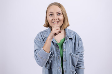 Woman in denim shirt showing silence gesture with finger