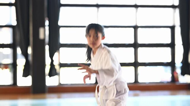空手道場で稽古に励む道着姿の小学生の女の子。真剣な表情で突きを放つ格闘技の習い事風景