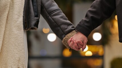 Close-up of a couple holding hands while wearing warm winter jackets outdoors