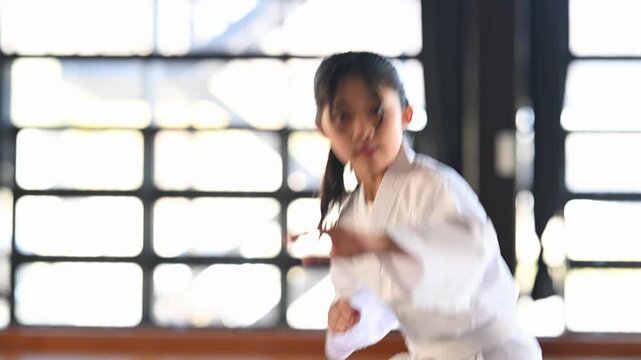 空手道場で稽古に励む道着姿の小学生の女の子。真剣な表情で突きを放つ格闘技の習い事風景