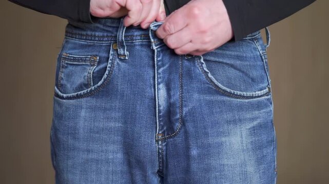 Man zipping up blue jeans with both hands. Zip up your trousers after going to bathroom