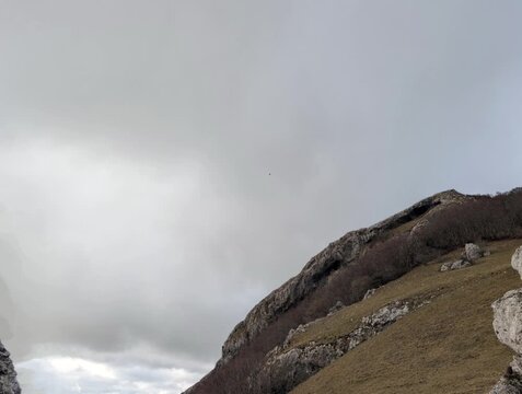 Formazioni rocciose esposte e vegetazione rada caratterizzano questa scena naturale selvaggia, ideale per progetti legati a natura, trekking, geologia e ambientazioni moody