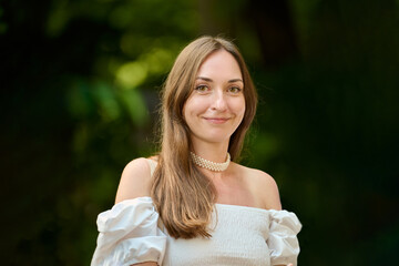 Naklejka premium Young woman with long brown hair smiling in natural outdoor setting