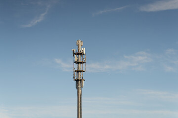 Fototapeta premium Tall cellular communication tower standing against a clear blue sky during daylight hours, providing mobile network signals