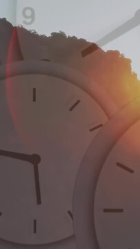 Vertical video: Sun rising at right edge causing clocks rotating CW, ridge lighting, showing time
