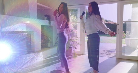 Naklejka premium Singing two women performing with microphones in sunlit living room near patio doors, lens flare