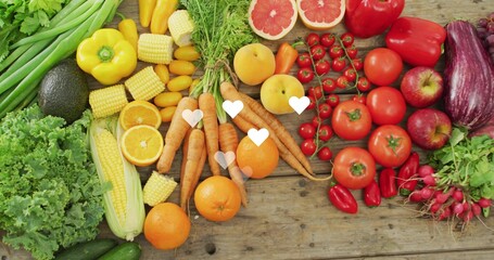Displaying carrots, oranges, tomatoes, corn on rustic wooden tabletop, with heart overlays © vectorfusionart
