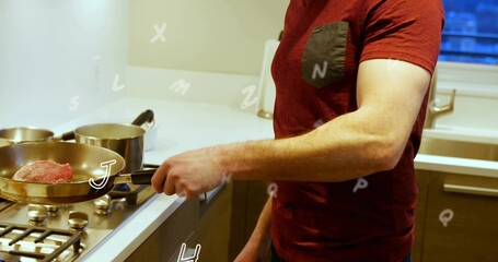 Holding man wearing maroon T-shirt gripping frying pan with raw meat in kitchen over stove, pots