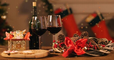 Displaying pair of red-wine glasses sitting on wood table at home, corked bottle, wreath glowing