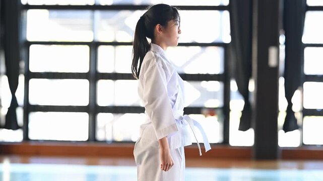 道場で気合の掛け声を出す空手着の女の子の横顔
