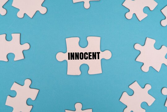 INNOCENT word alphabet letters on puzzle surrounded by puzzle pieces. A conceptual metaphor for justice, legal defense and truth