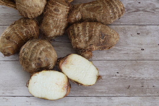 Taro root vegetable corms on rustic wooden background
