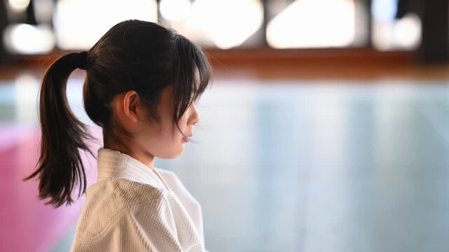 道場で気合の掛け声を出す空手着の女の子の横顔