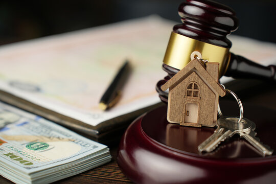 Real Estate Law and Property Auction Concept. Judge's gavel, house keys, money, and legal documents on a desk. Represents foreclosure, property law, or real estate auctions