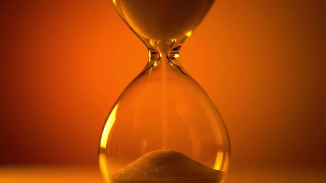 Classic hourglass slowly measuring the passage of time against warm light