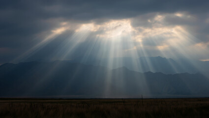 Dramatic Sunbeams Piercing Through Dark Clouds Over Mountain Range