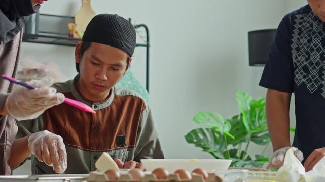 Young man in skullcap carefully making cookies with family members
