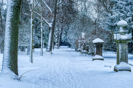 Verschneiter Weg auf einem historischen Friedhof in D&uuml;sseldorf im Winter