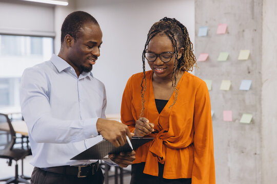 African American business colleagues collaborating on document, discussing ideas and planning project in modern office environment