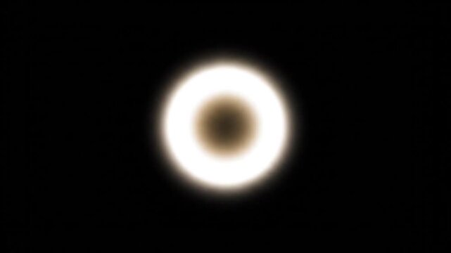 A bright white circle glows in the dark night sky with nothing around.