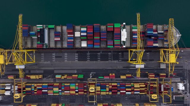 Aerial view of a cargo ship laden with colorful containers and bright yellow cranes, docked at the port, a vibrant scene of global trade, Trieste, Friuli-Venezia Giulia, Italy.