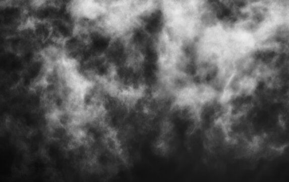 Monochromatic wispy smoke texture against dark moody stormy backdrop