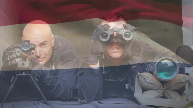 Two troops prone, marksman aiming, spotter raising binoculars, scanning targets, flag drifting