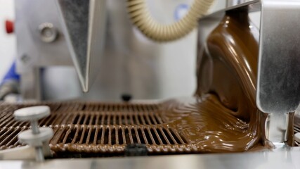 Liquid chocolate pouring on conveyor belt in factory