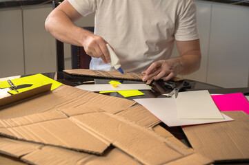 Close-up of hands working on a cardboard prototype at a desk. Startup project concept, product development, prototyping process, creativity, and innovation. Hands-on work, no face visible.