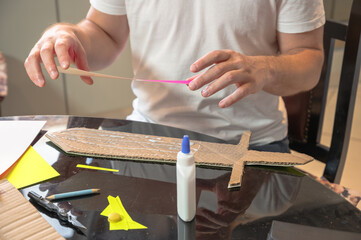 Close-up of hands working on a cardboard prototype at a desk. Startup project concept, product development, prototyping process, creativity, and innovation. Hands-on work, no face visible.