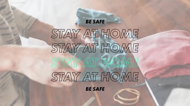 Animation of words Be Safe Stay at Home flashing over a person sewing coronavirus Covid19 masks