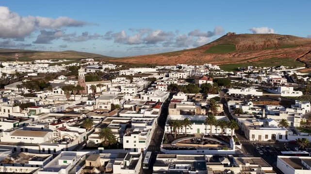 Aerial view of the white buildings contrasting with the brown mountain landscape and the castle, Teguise, Canary Islands, Spain.