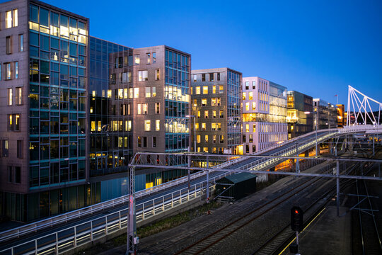 Corporate skyline at twilight shows modern bridge architecture above railway in urban Oslo Barcode area Norway with iconic city infrastructure